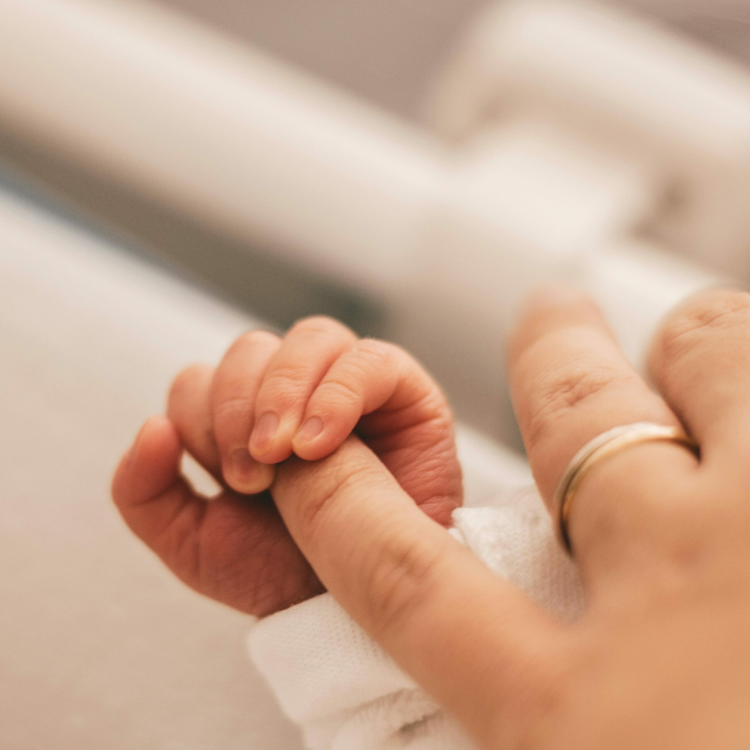 un nouveau-né tient le doigt de sa maman. Cela illustre le fait de consigner dans un livre, un instant de vie