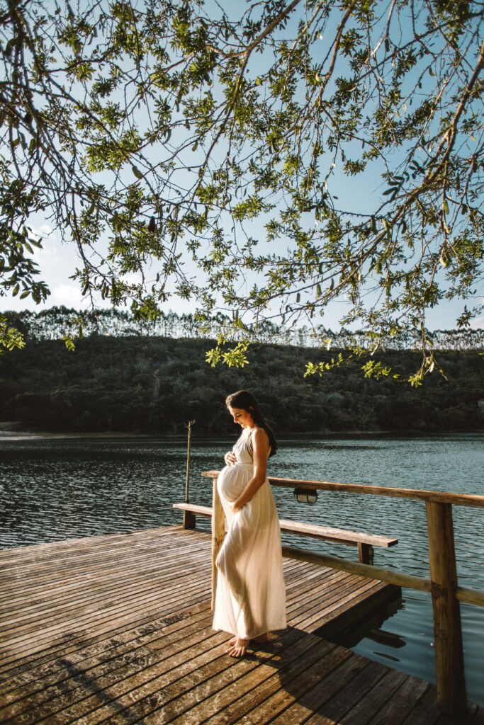 Raconter son récit de grossesse une femme enceinte est sur un ponton au bord d'un lac. Cela représente la possibilité de raconter une grossesse, chapitre important de sa vie, dans un livre biographique.