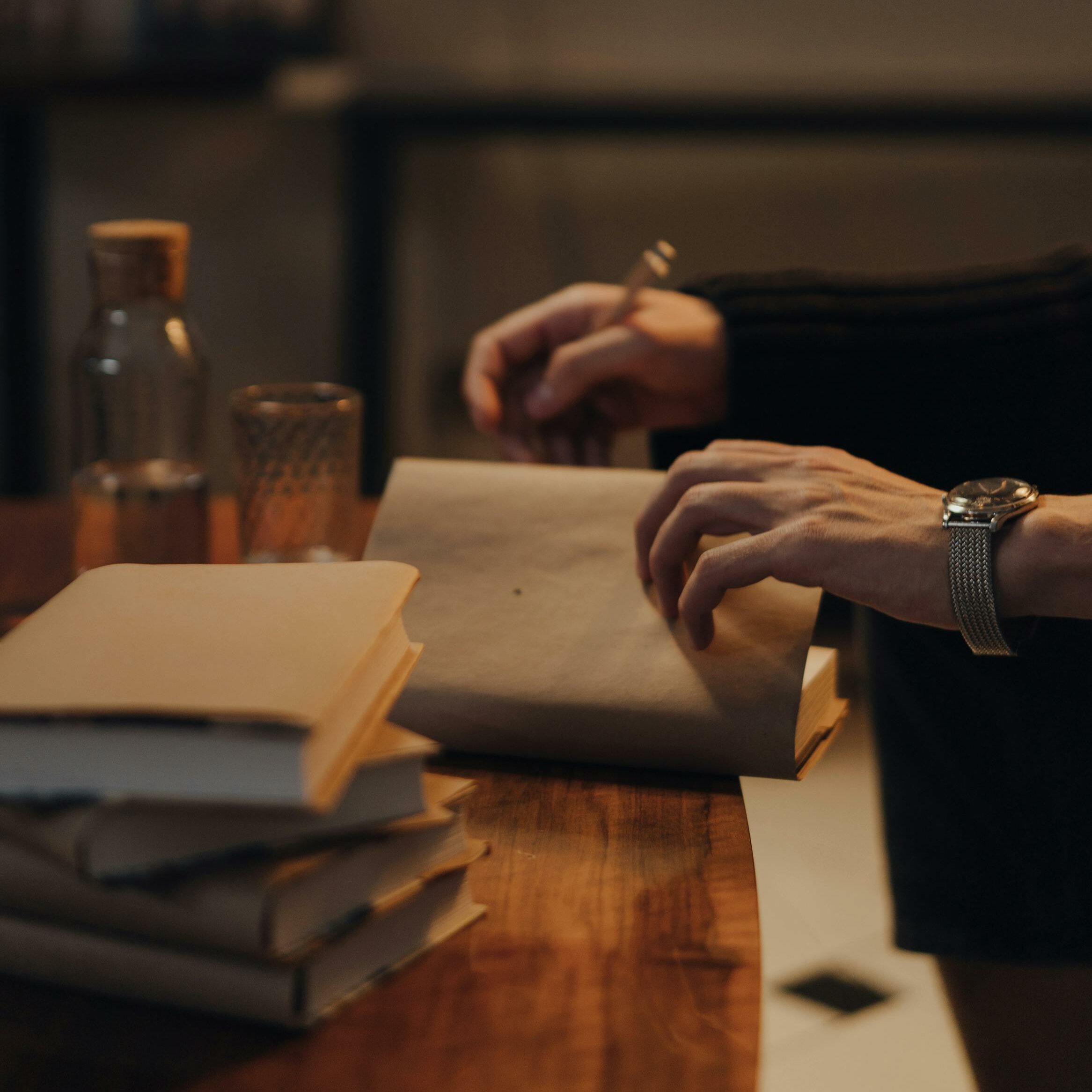 une main signe un ouvrage et une pile d'un ouvrage identique est posée sur le bord de la table pour évoquer l'édition éventuelle du livre biographique.