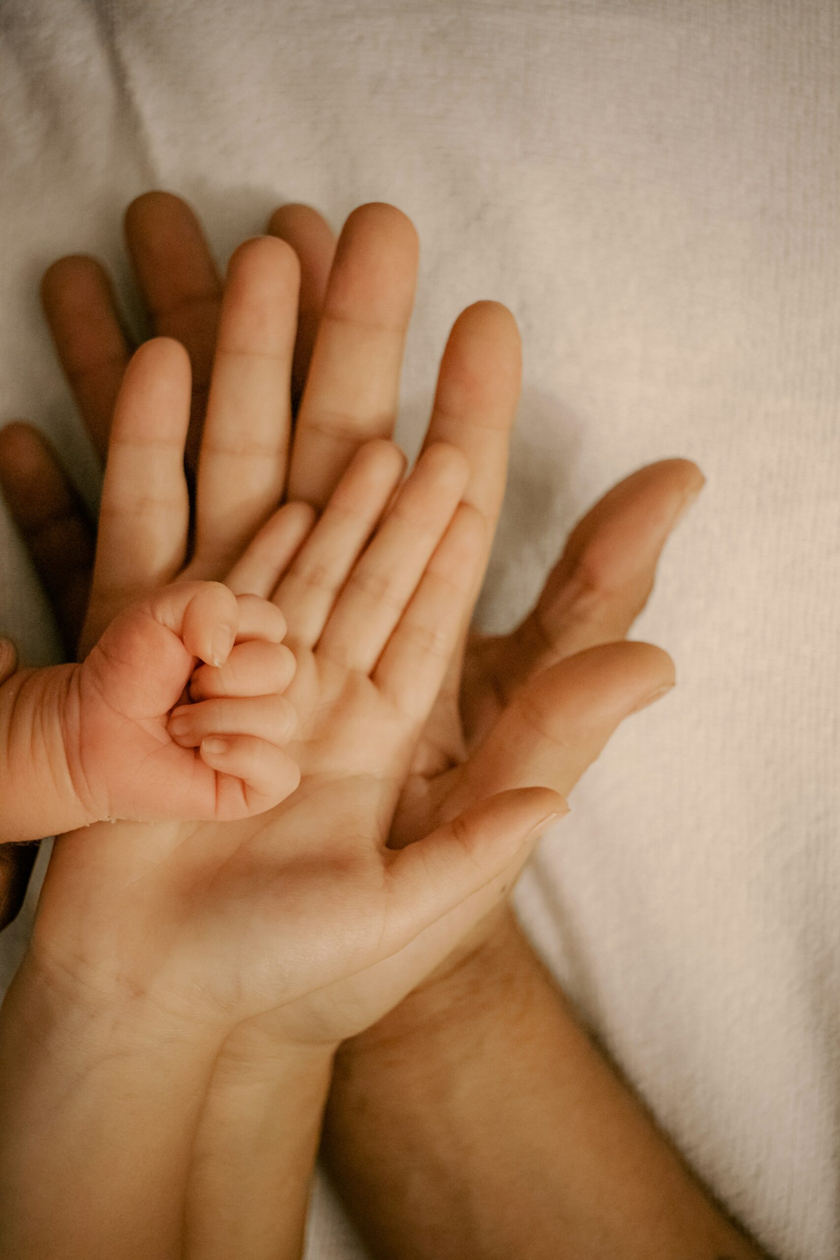 Sauvegarder les souvenirs de son nouveau rôle de parent superposition de trois mains: celle de chaque parent et du bébé pour illustrer un chapitre important de sa vie : devenir parent.