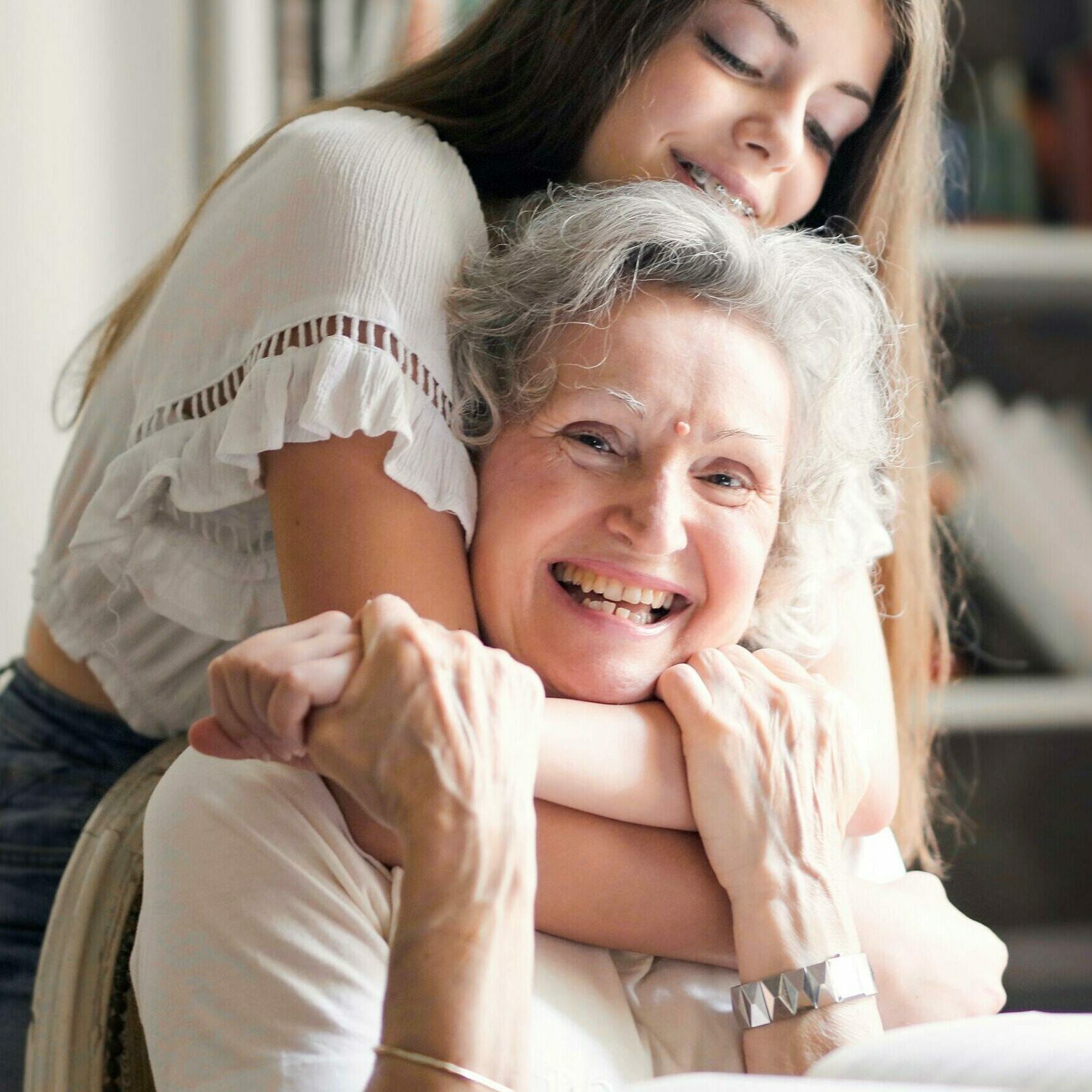 Une petite-fille enlace sa mamie. Cette photo illustre l'offre pour acheter une biographie d'une vie entière.