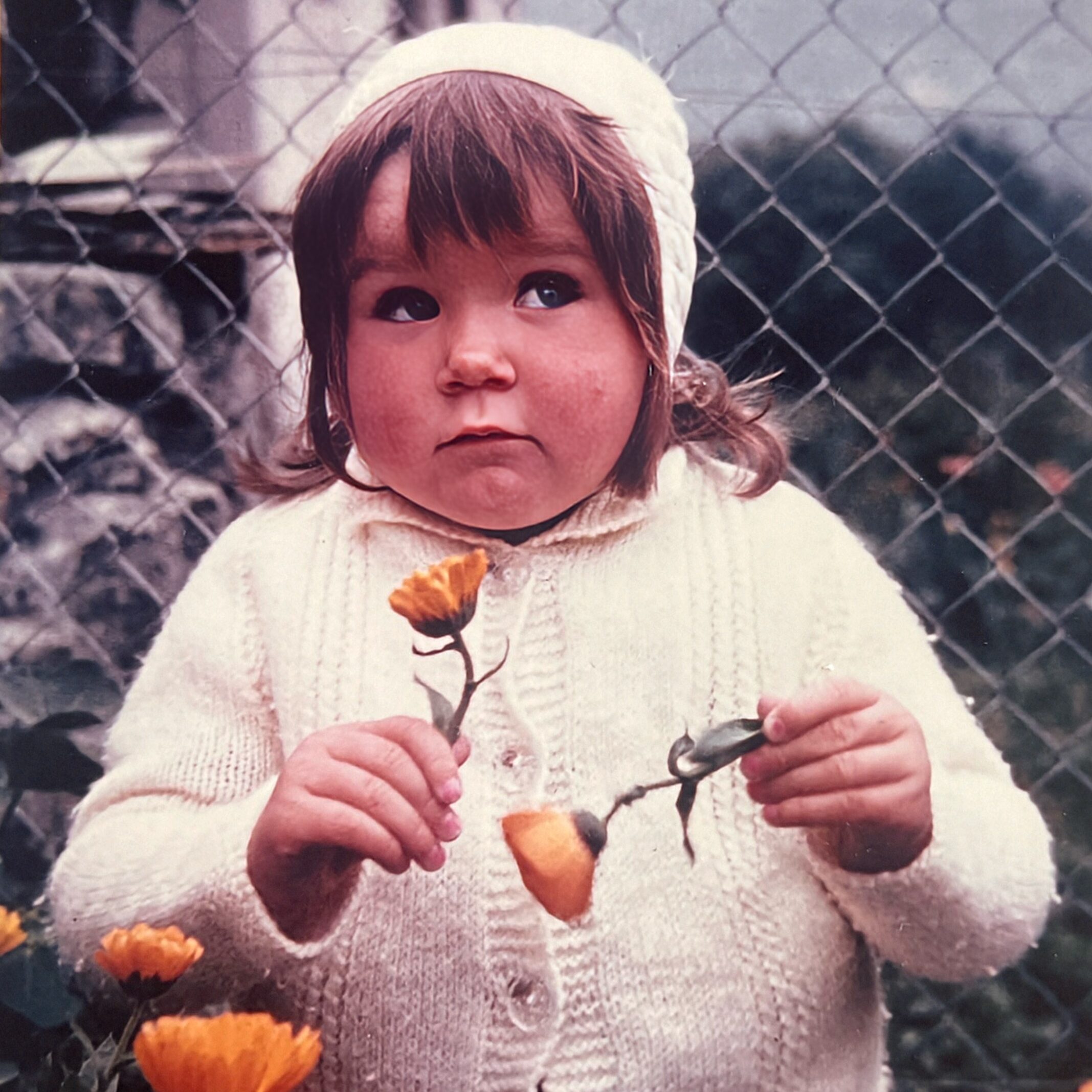Ecrire sa jeunesse Une petite fille cueille des fleurs oranges, cela illustre le fait d'écrire un chapitre important de sa vie : l'enfance.
