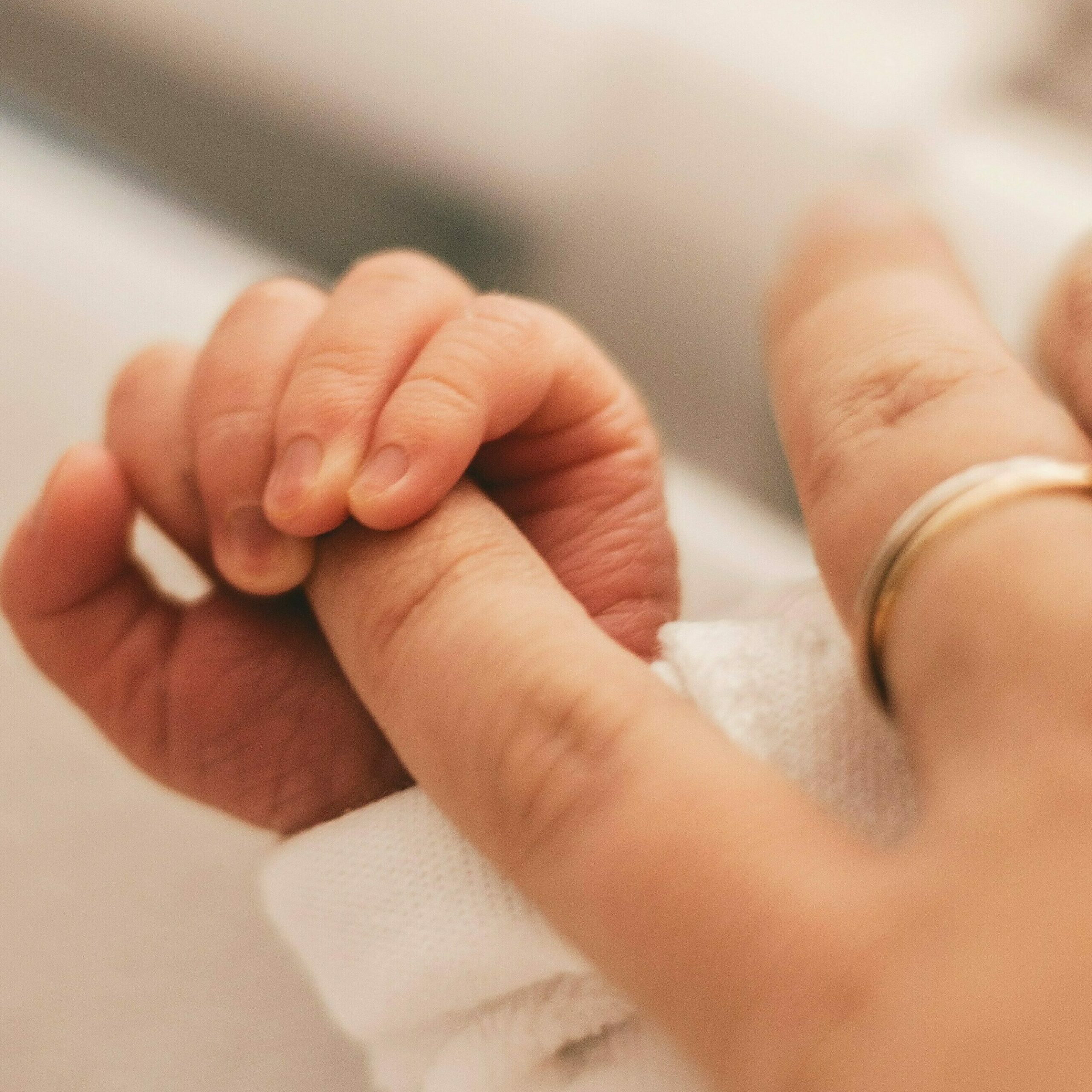 main d'un nouveau né serrant le doigt de sa maman