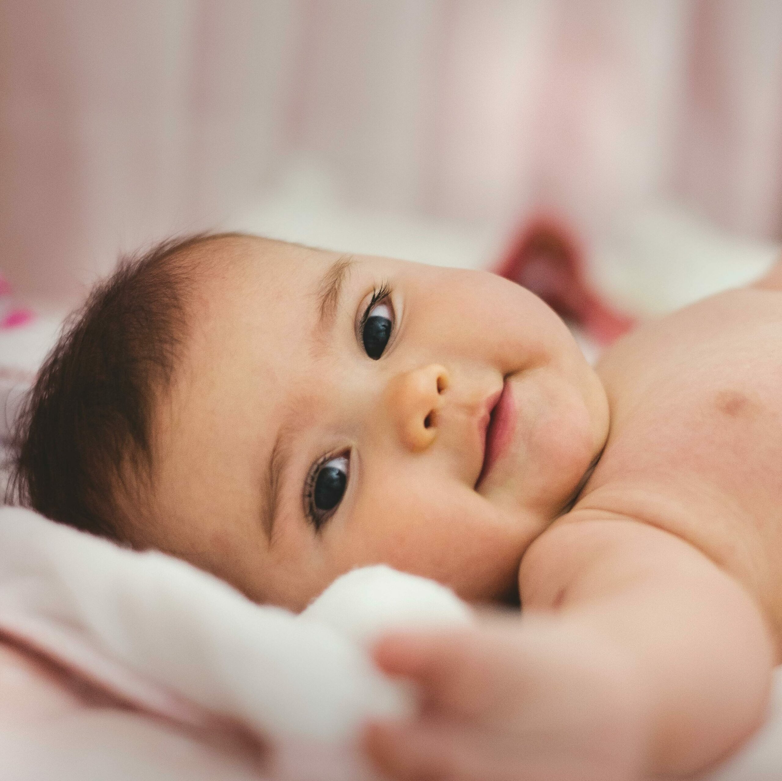 Raconter une adoption un bébé en bas âge sourit en regardant l'objectif. Cette photo illustre le fait de raconter une adoption.