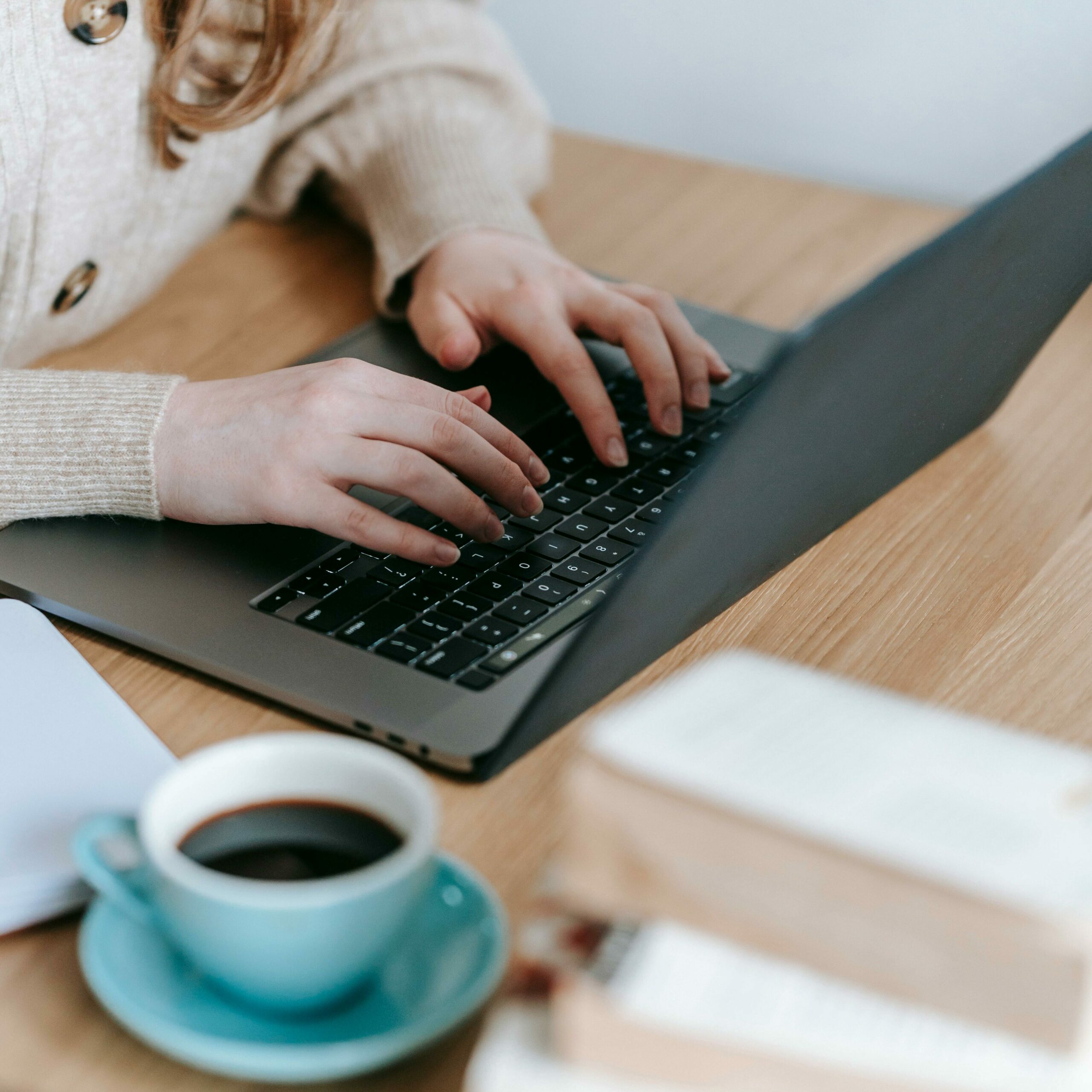 Ecrire un chapitre de sa vie une femme pianote sur son ordinateur entourée de livres et d'une tasse de café.