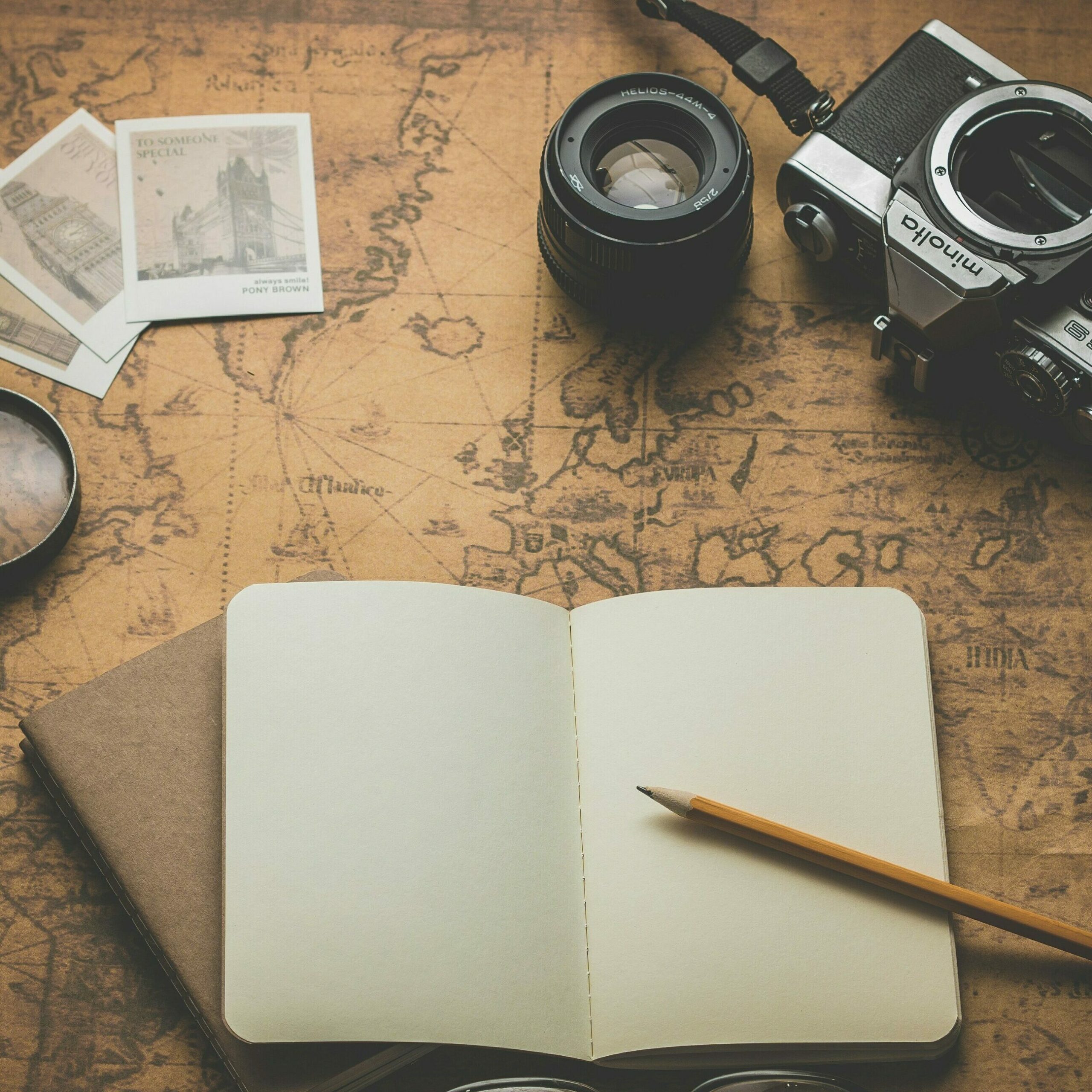 Sauvegarder des souvenirs de voyage image illustrant le thème du voyage, figurent dessus : un carnet, une carte du monde, une loupe et un appareil photo. Ce peut être un chapitre de vie important pour soi qu'on souhaite retranscrire.