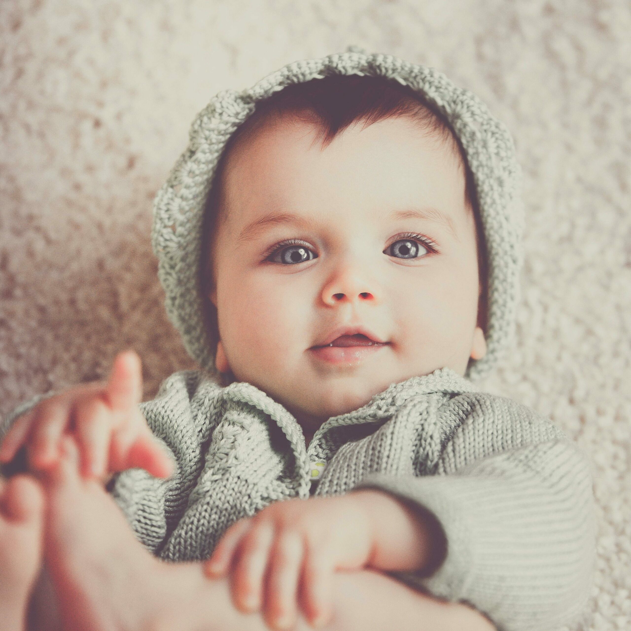 Un bébé sourit en regardant l'objectif. Cela illustre le fait qu'on puisse raconter les premiers mois de vie de son enfant dans un livre biographique relatant un chapitre de vie. 